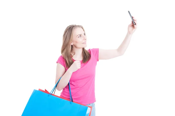 Hermosa chica sosteniendo bolsas de compras y tomando selfie con la celda —  Fotos de Stock