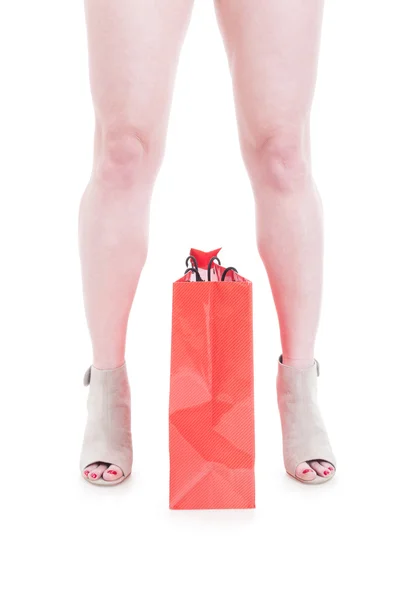 Primer plano de la bolsa de compras roja entre hermosas piernas de mujer —  Fotos de Stock