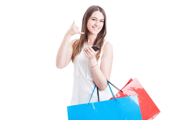 Happy beautiful shopper holding cell phone and doing a call gestu — стоковое фото