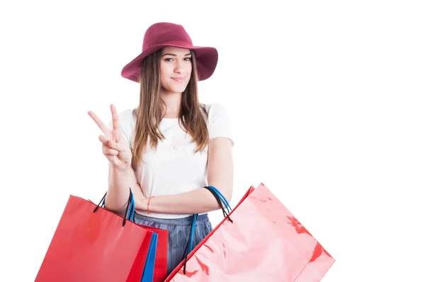 Sonriente chica bonita haciendo la victoria o signo de paz en las compras — Foto de Stock