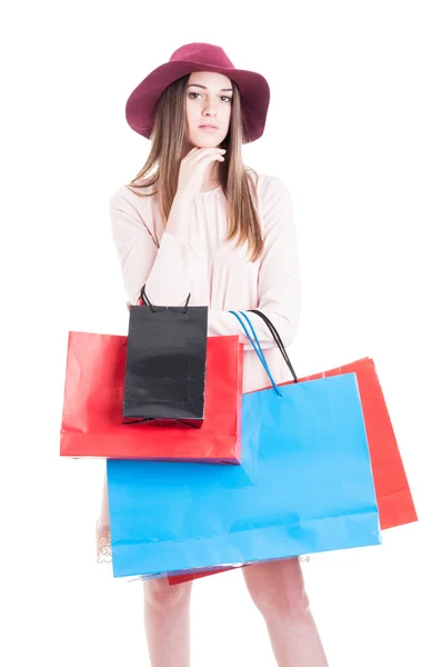 Joven chica seria usando vestido y sombrero sosteniendo bolsas de regalo — Foto de Stock