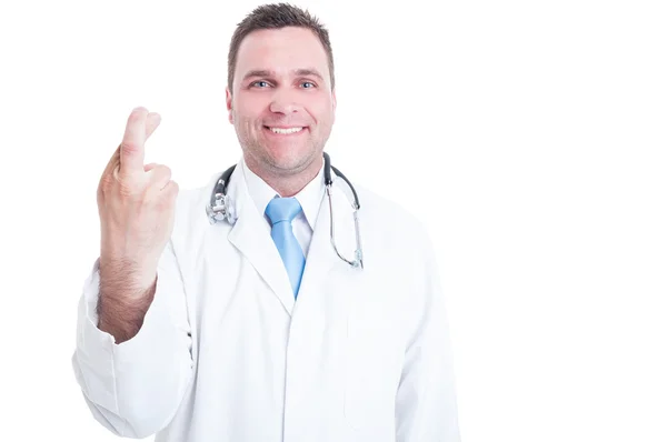 Médico masculino sonriendo y mostrando los dedos cruzados con una mano — Foto de Stock