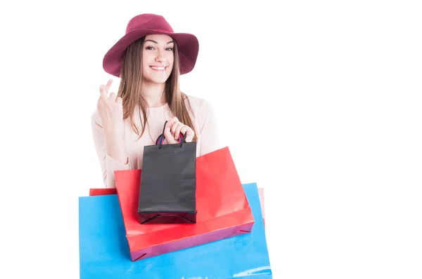 Jovencita alegre con los dedos cruzados y bolsas de compras —  Fotos de Stock