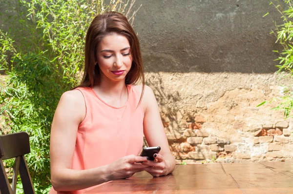 Donna seduta sulla terrazza e sms su smartphone — Foto Stock