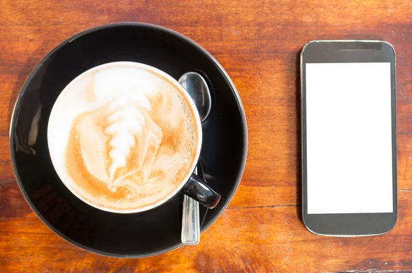 Крупный план чашки кофе и смартфона в сторону — стоковое фото
