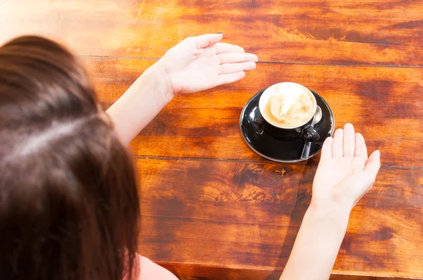 Женщина сидит на террасе и показывает чашку кофе — стоковое фото