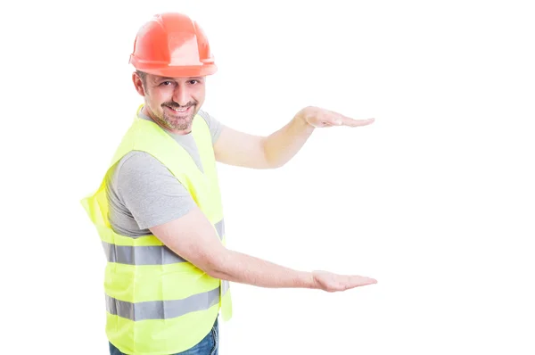 Knappe constructor houden iets onzichtbaar in zijn palmen — Stockfoto