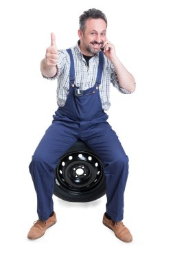 Smiling technician talking on cellphone and thumb up clipart