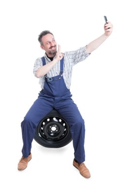 Neşeli tamirci lastik üzerinde oturuyor ve selfie çekiyor