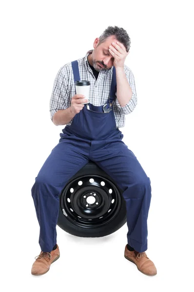 Yorgun tamirci lastik üzerinde oturan ve kahve içme — Stok fotoğraf