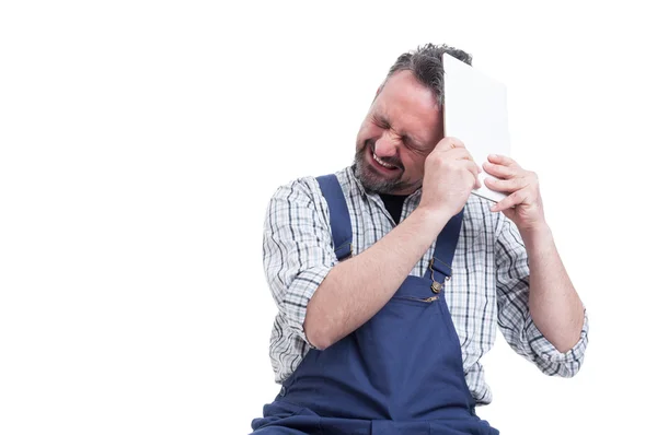 Angry repairman hitting head with digital tablet — Stock Photo, Image