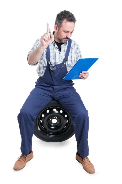 Busy engineer on garage writing on clipboard — Stock Photo, Image