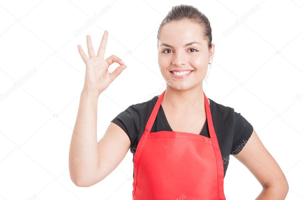 Cheerful female employee on supermarket doing ok sign