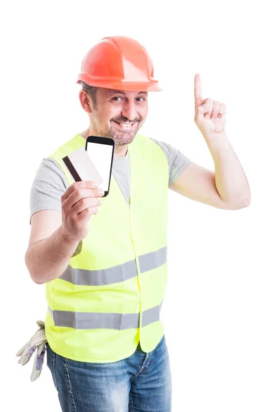 Constructor con tarjeta de débito y teléfono apuntando hacia arriba — Foto de Stock
