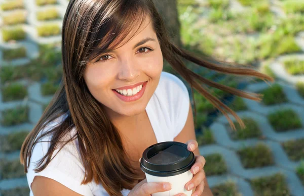 Hermosa chica sosteniendo café afuera en el parque y sonriendo —  Fotos de Stock