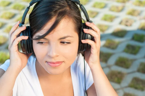 Girl holding headphones and listening to music — Stock Photo, Image