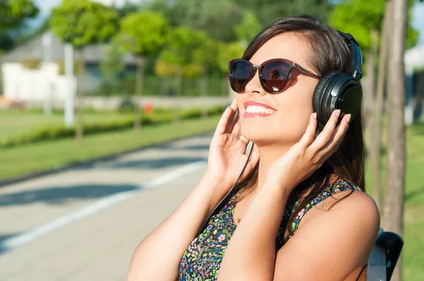 Beautiful girl smiling and holding her headphones — Stock Photo, Image