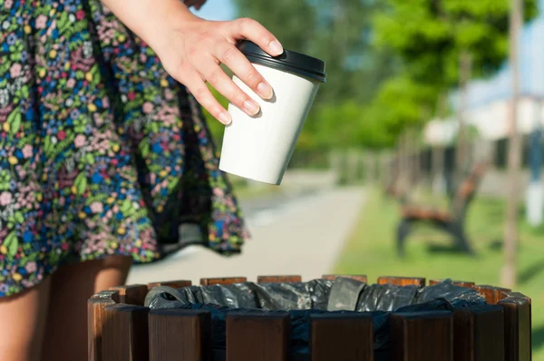 Крупный план женская рука бросает бумажный стаканчик на мусор — стоковое фото