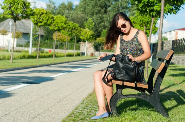 Menina sentada no banco na mochila de abertura do parque — Fotografia de Stock