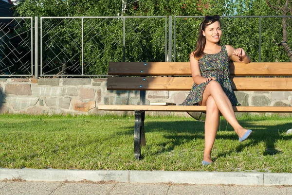 Linda senhora sorrindo sentado no banco no parque — Fotografia de Stock