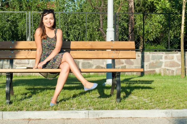 Femme posant dans le parc assis sur le banc et souriant — Photo