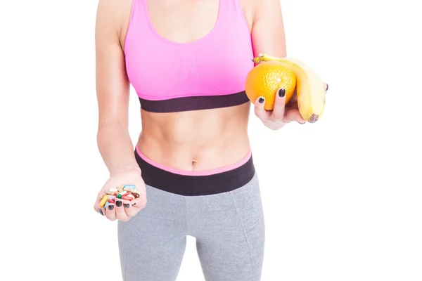 Chica usando ropa deportiva elegir frutas sobre pastillas — Foto de Stock