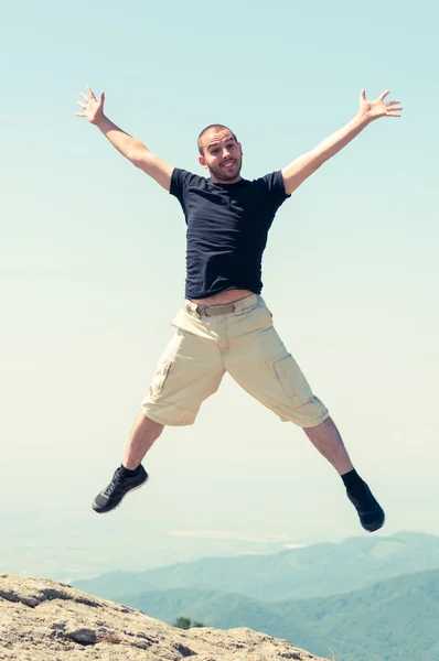Homem feliz pulando no topo da montanha — Fotografia de Stock