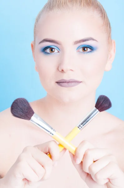 Портрет дівчини, що позує з перехрещеними пензлями для макіяжу — стокове фото
