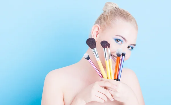 Chica sosteniendo maquillaje cepillos profesionales y sonriendo — Foto de Stock