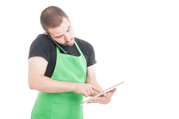 Supermercado vendedor estar ocupado com telefone e tablet — Fotografia de Stock