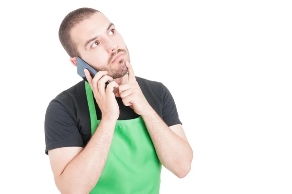 Male supermarket employee making thinking gesture at phone — Stock Photo, Image