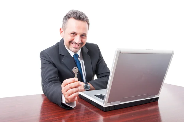 Homme de l'immobilier au bureau montrant clé — Photo