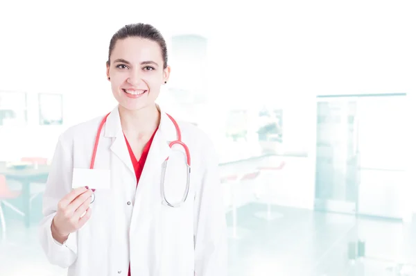Médico sonriente en uniforme mostrando tarjeta de visita — Foto de Stock