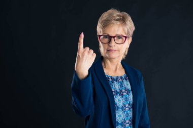 Yaşlı sekreter mavi ceket giyiyor.