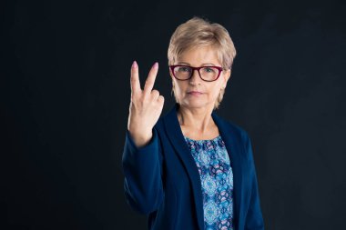 Yaşlı sekreter iki numarayı mavi ceket giyerken gösteriyor.