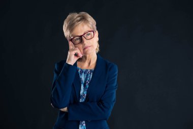 Mavi jaket ve gözlük takan yaşlı bir sekreterin portresi.