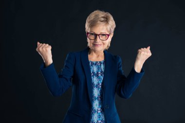 Kıdemli avukat karanlık bir arkaplanda başarı işareti yapıyor.