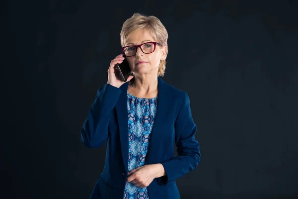 Пожилая Деловая Женщина Разговаривает Мобильному Телефону Тёмном Фоне — стоковое фото