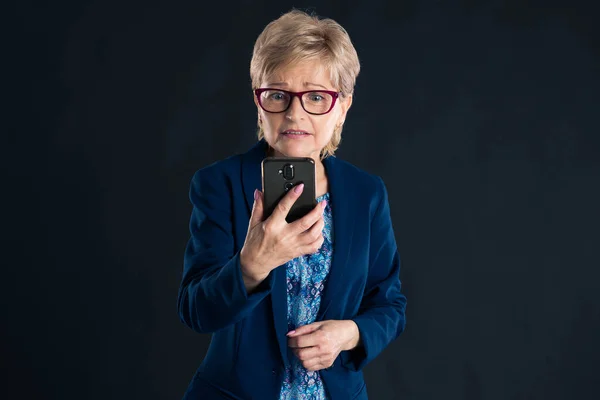 Пожилая Деловая Женщина Разговаривает Мобильному Телефону Выглядит Обеспокоенной Тёмном Фоне — стоковое фото