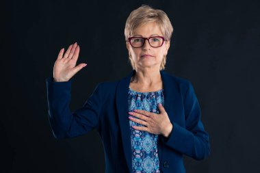 Yaşlı sekreter küfür ediyor ve mor gözlüklü mavi bir ceket giyiyor.