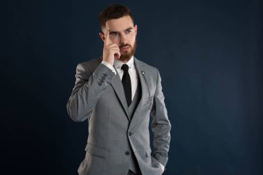 Yakışıklı genç işadamı gri takım elbise ve siyah kravat takmayı düşünüyor.