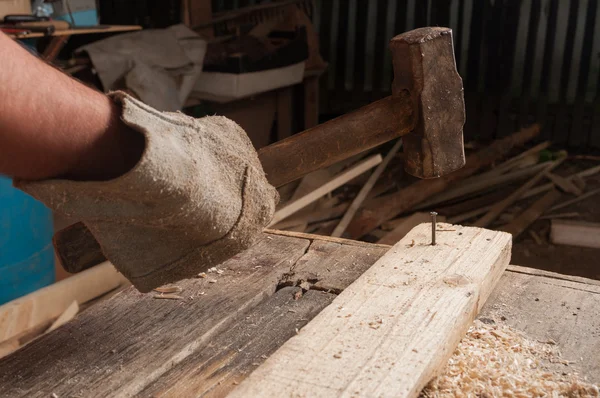 Schreiner schlägt mit Hammer Nagel auf Holz — Stockfoto