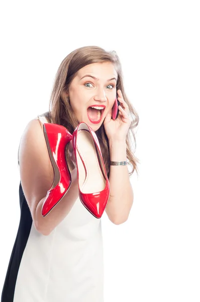 Mujer excitada sosteniendo zapatos rojos y llamando a amigos — Foto de Stock