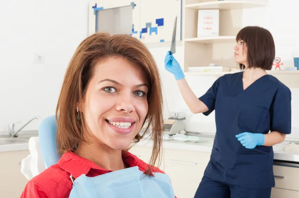 Patientin lächelt und Zahnärztin untersucht Röntgenbild — Stockfoto