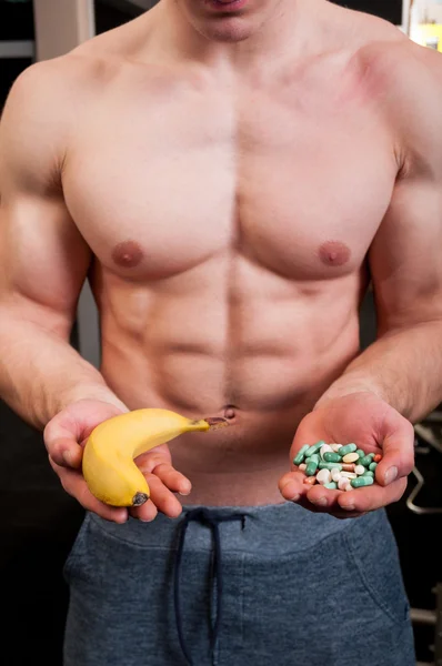 Muskel man val mellan banan och piller — Stockfoto