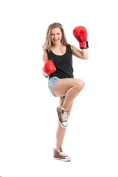 Young woman wearing boxing gloves and raising foot and hand — Stock Photo, Image