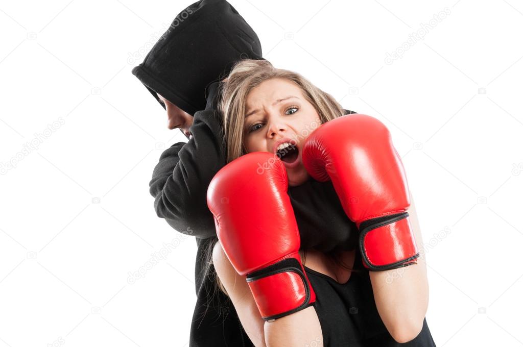 Male aggressor grabbing a frightened woman wearing boxing gloves