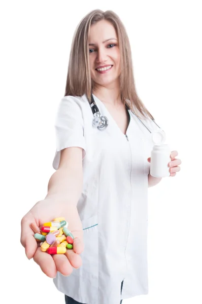 Young and friendly woman doctor holding and offering pills — Stock Photo, Image