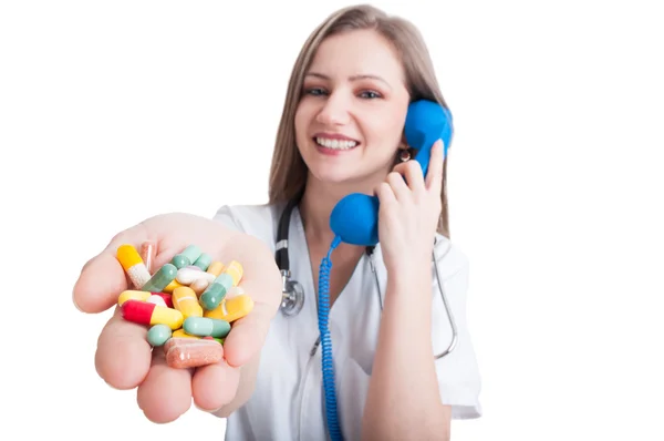 Woman doctor talking on the phone and offering pills — Stock Photo, Image