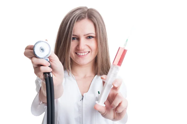 Young female doctor presenting stethoscope and syringe — Stock Photo, Image